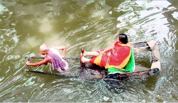 A woman in a hand pulled rickshaw in a flood. Photo Credit: http://travelbeats.indianeagle.com/