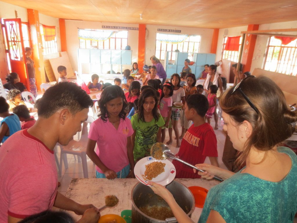 Elsa and her boyfriend serving food at her community center in the philippines