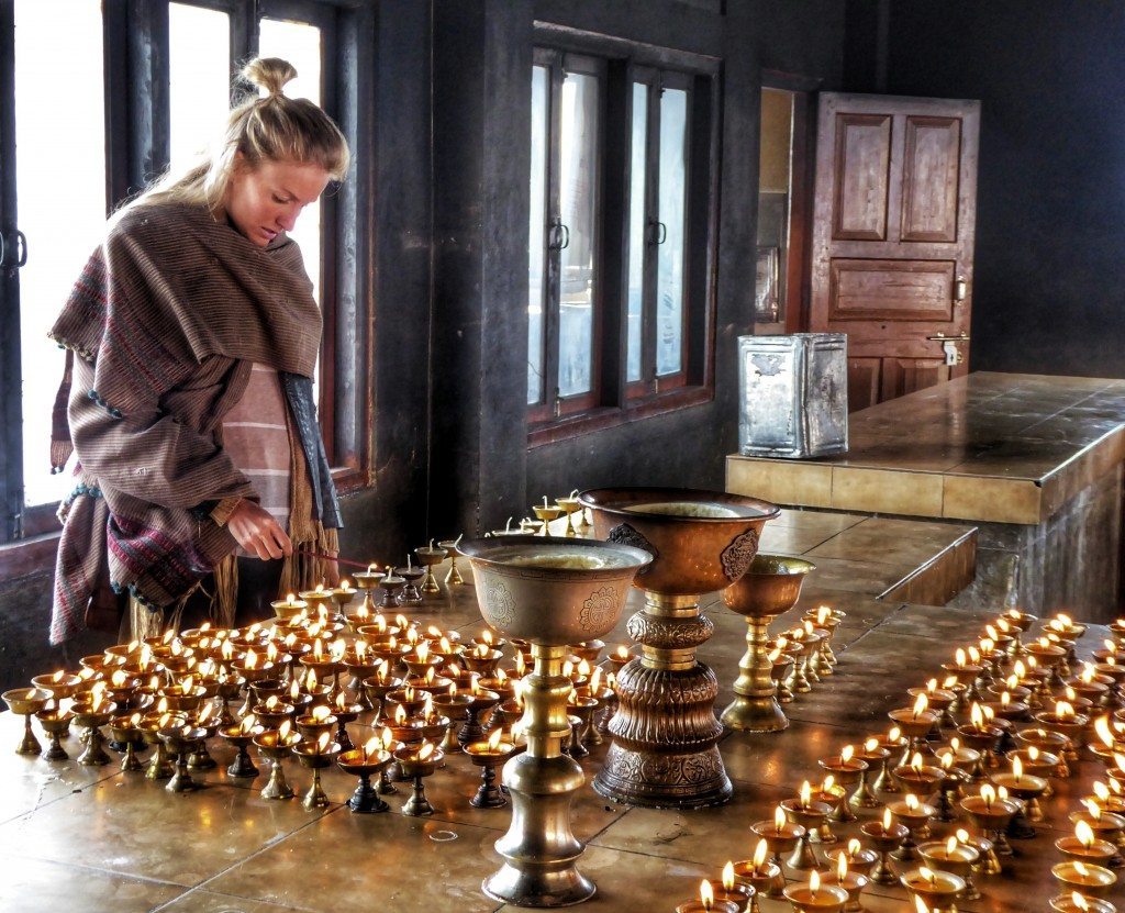 lighting a yak butter lamp in a Tibetan Buddhist monastery in Tawang