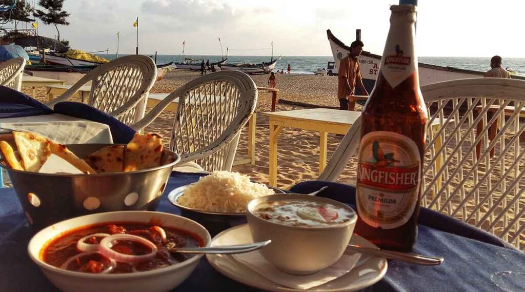 curry and kingfisher on the beach in goa