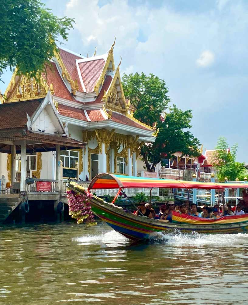 longtail boat on bangkok canal with temple