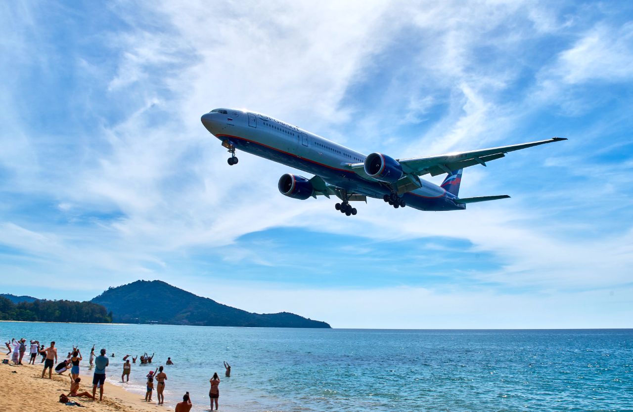plane flying over mai khao beach in phuket OP
